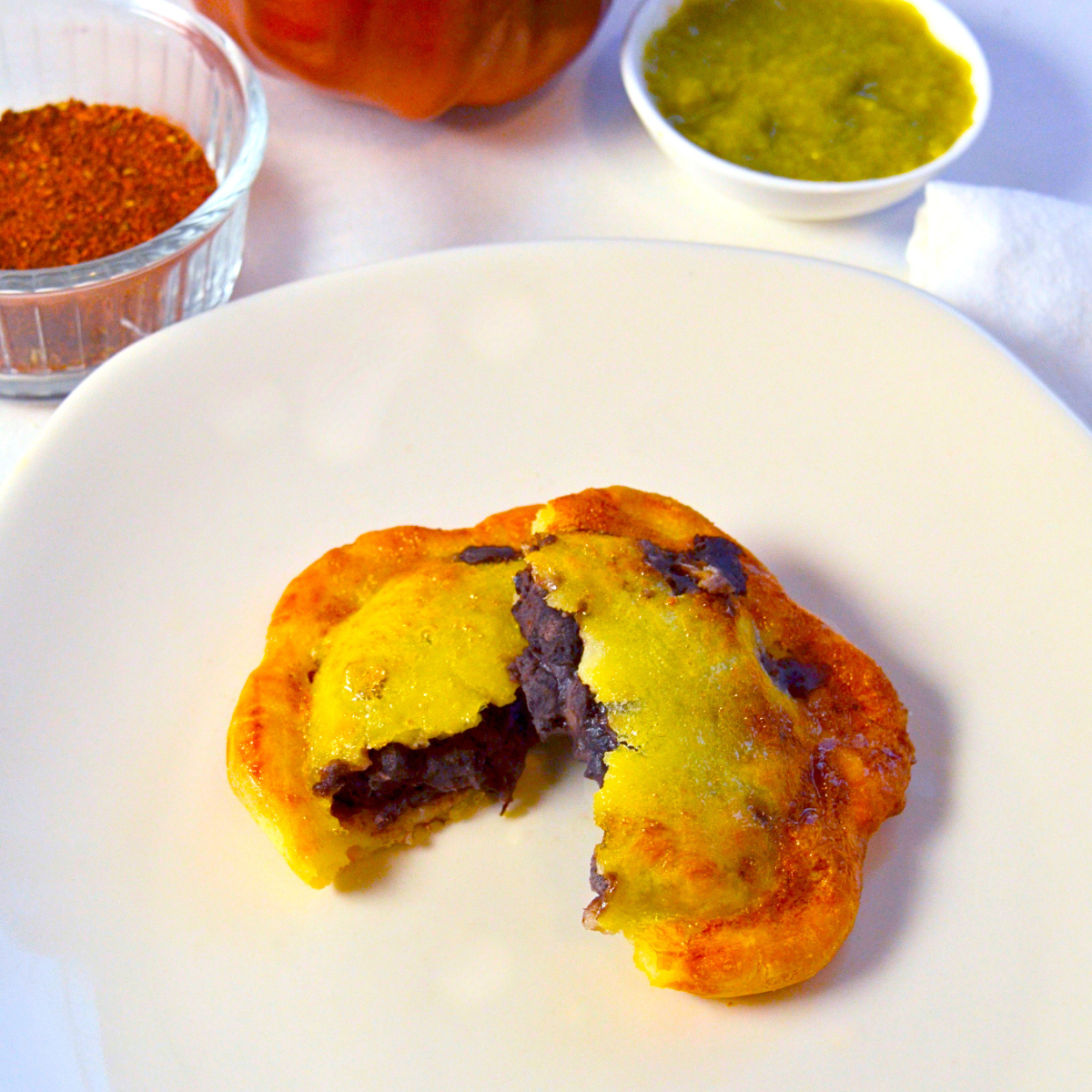 Gluten-free Vegan Oaxacan Black Bean Empanoli—flaky hand pies filled with smoky, seasoned black beans, served on a white plate with salsa.