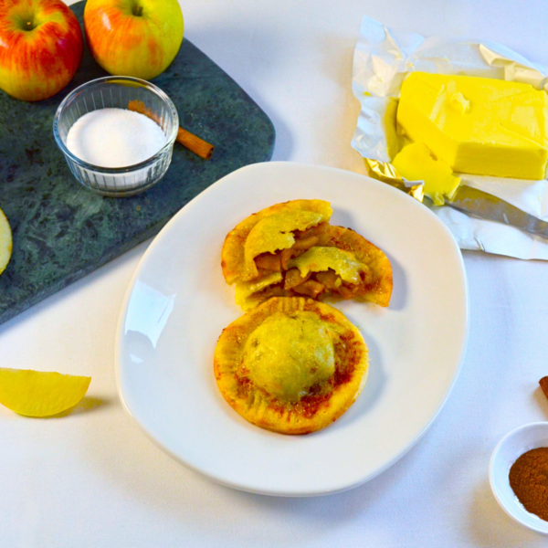 Gluten-free Honeycrisp Apple Empanoli—golden, flaky hand pies filled with cinnamon-spiced Honeycrisp apples, served on a white plate.