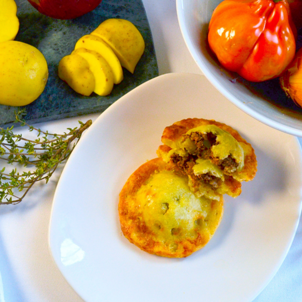 Gluten-free Picadillo Beef Empanoli—crispy, golden hand pies filled with seasoned ground beef, potatoes, and warm spices, served on a white plate.