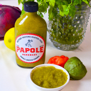 Papole Verde Sauce—zesty, tangy green sauce made with tomatillos and green chiles, displayed in a glass bottle with fresh ingredients.